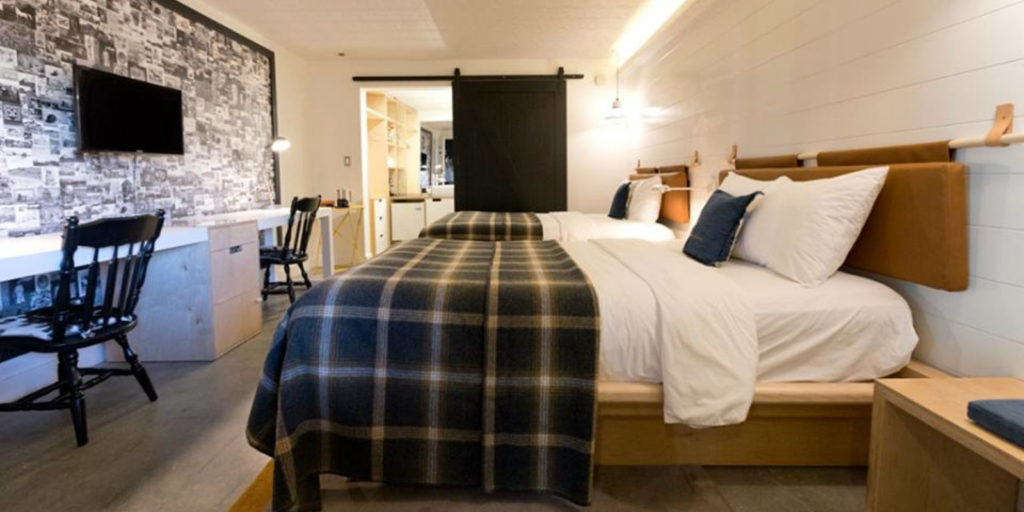 farm style hotel room with double beds draped in blue and cream farm inspired bedding