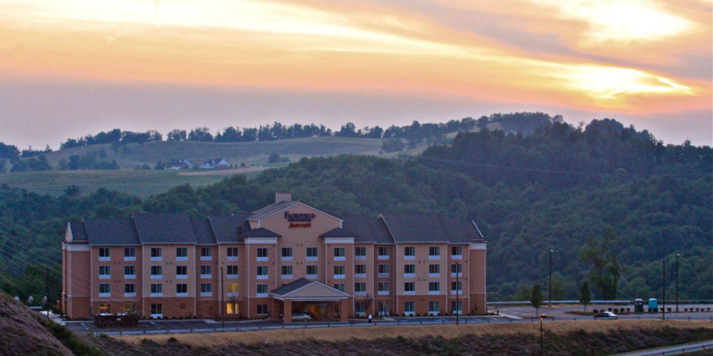 view of a four story hotel set infront of a mountain view at sunset