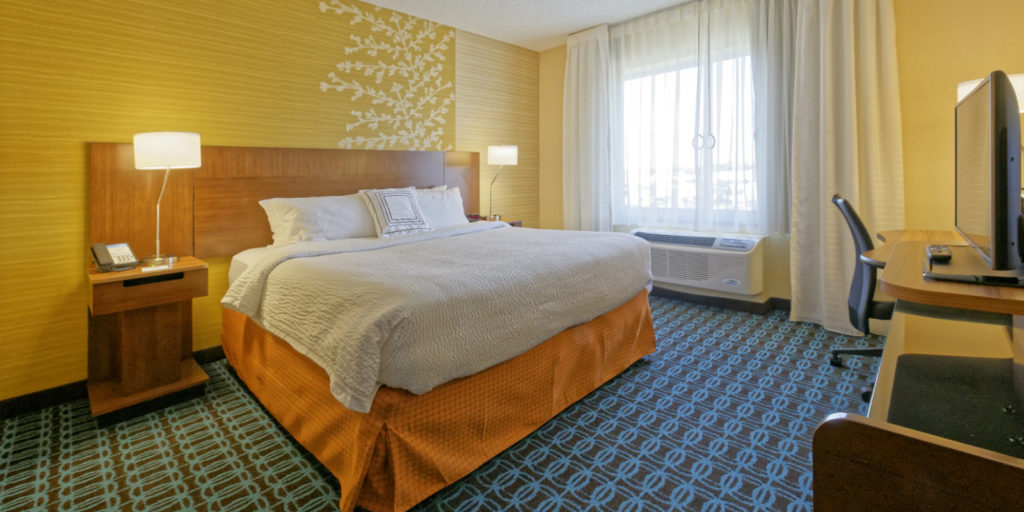 a hotel room decorated in golden yellows, oranges and blue with floral accents on the wall behind the bed