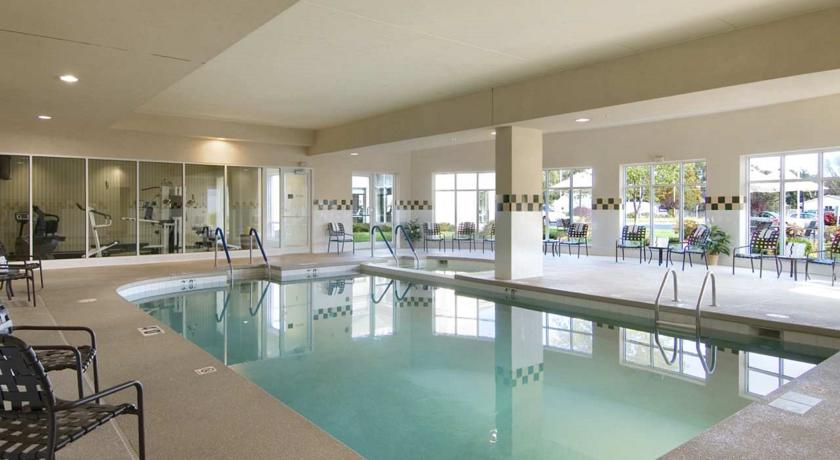 indoor swimming pool with black patio furniture and adjoining fitness center