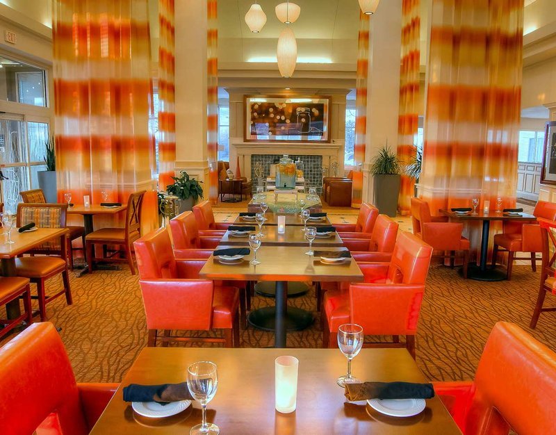 dining area decorated with bright oranges and golds with white chandaliers of different shapes hanging from the ceiling
