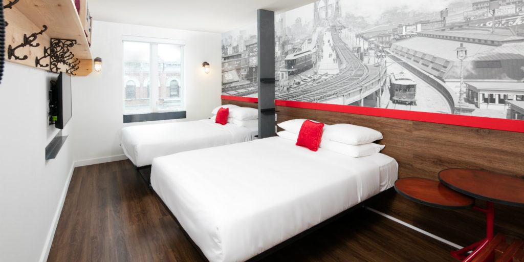 modern hotel room with a mural of a vintage scene of a railroad bridge running through a city