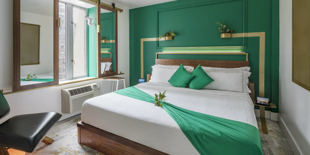 an art deco style hotel room with emerald green accent wall and gold accents