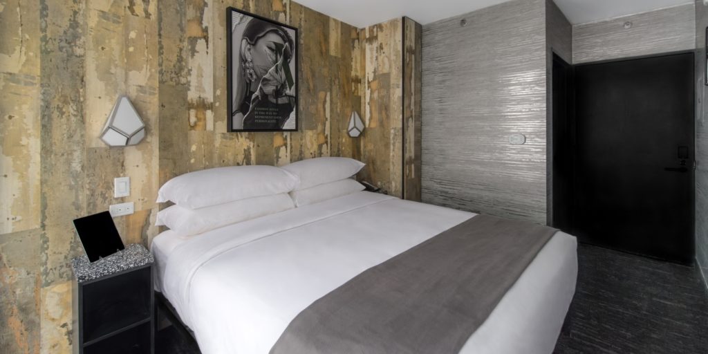 a modern hotel room with gray steely walls and abstract tile walls and modern art