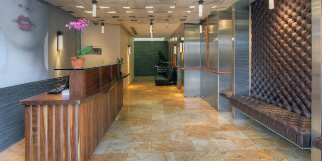 a modern hotel lobby with marble tile floors, leather benches and dark wooden check-in counter