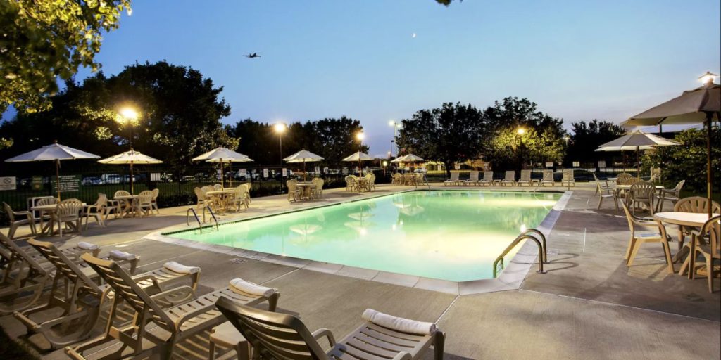 an outdoor swimming pool at dusk surrounded by patio chairs and tables